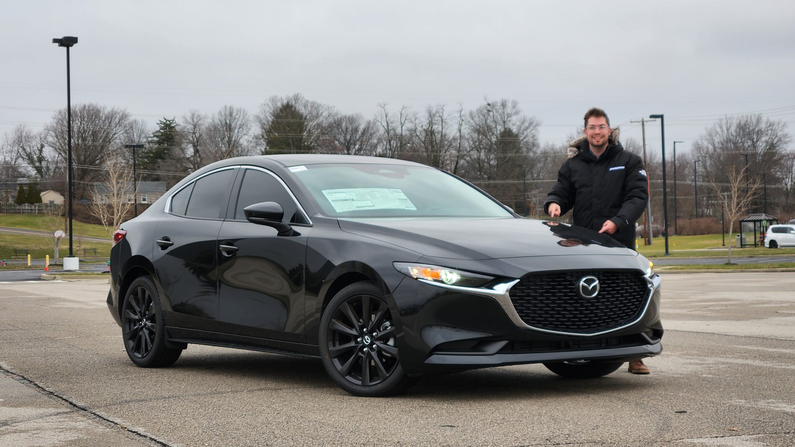 Front passenger side view of the 2026 Mazda 3 Sedan showcasing the bold black mesh grille and sleek headlight design.