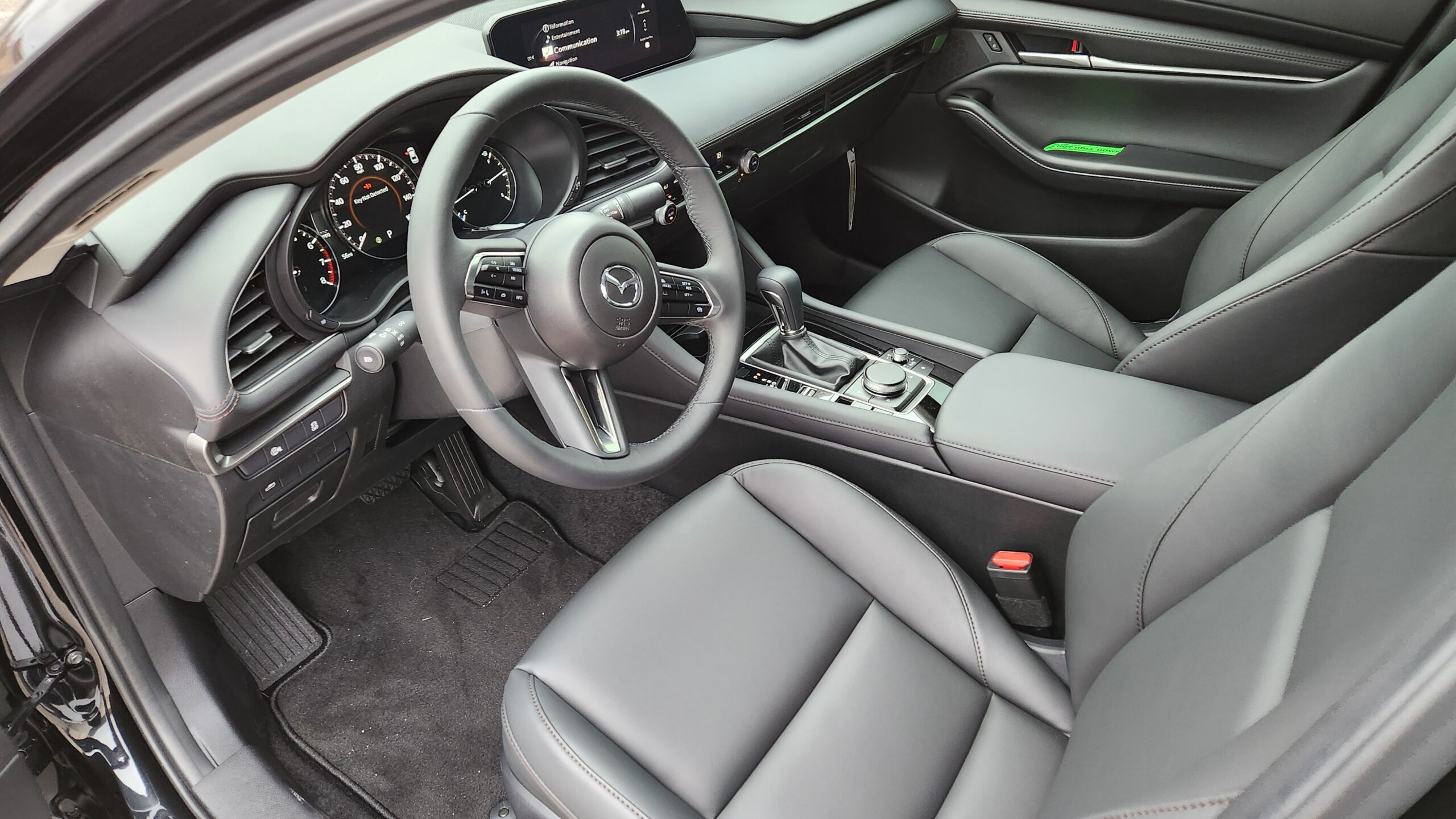 Interior view of the 2026 Mazda 3 Sedan featuring the steering wheel, premium seating materials, and rotary-controlled infotainment display.