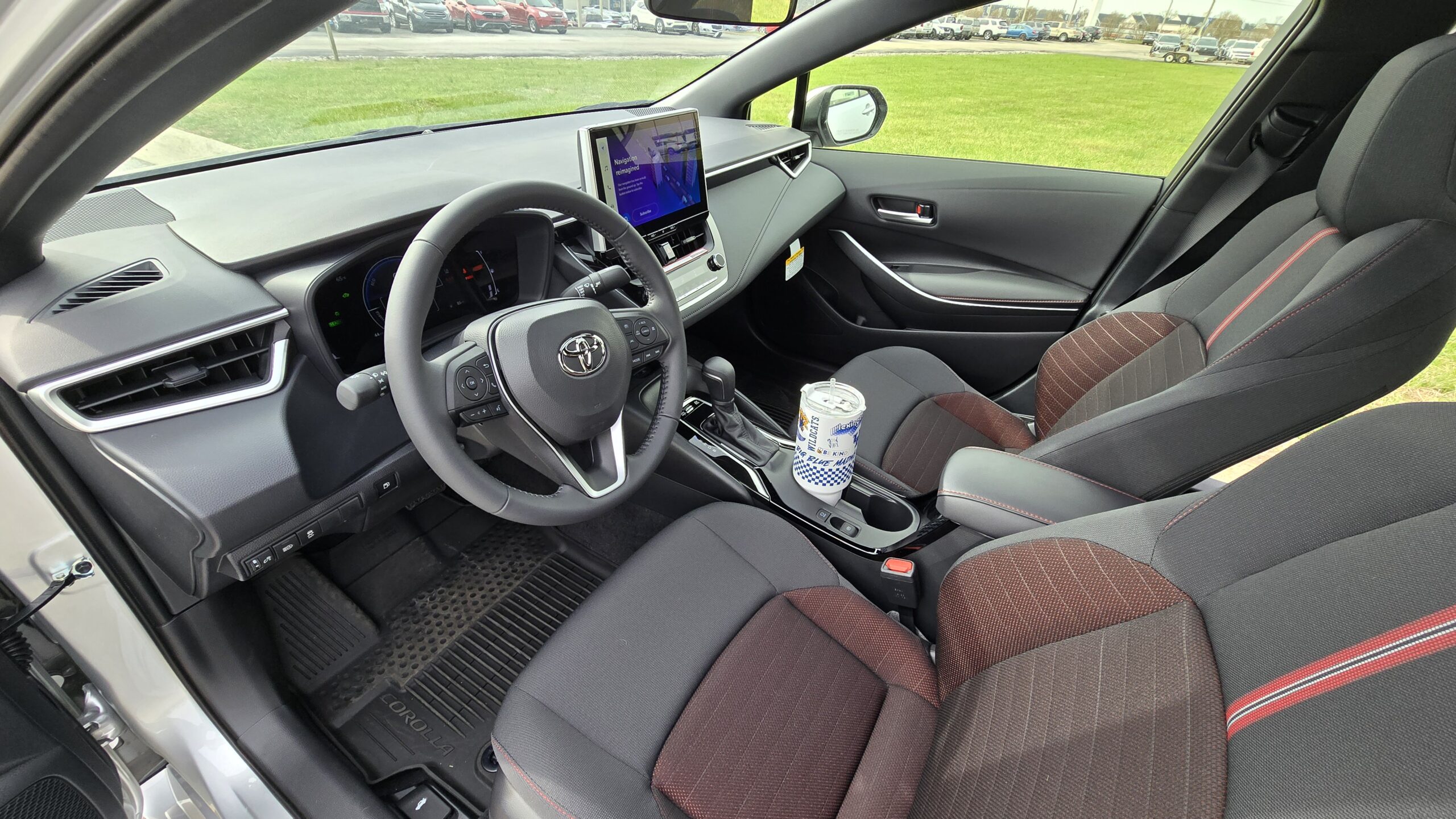 Interior cabin view of the 2026 Toyota Corolla showcasing the steering wheel, digital gauge cluster, and infotainment screen.