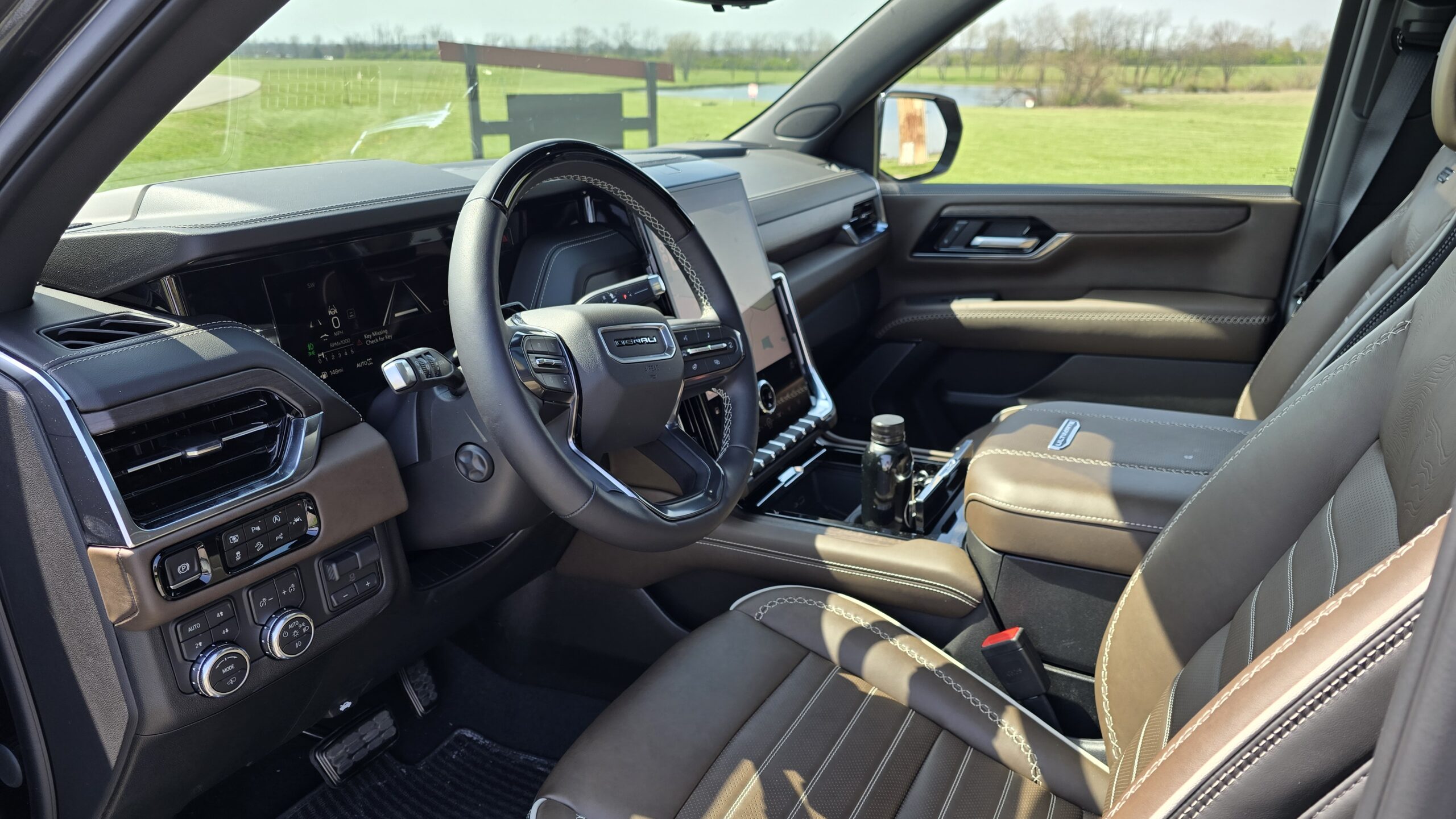 Interior view of the 2026 GMC Yukon dashboard, focusing on the steering wheel and the large vertical infotainment touchscreen.
