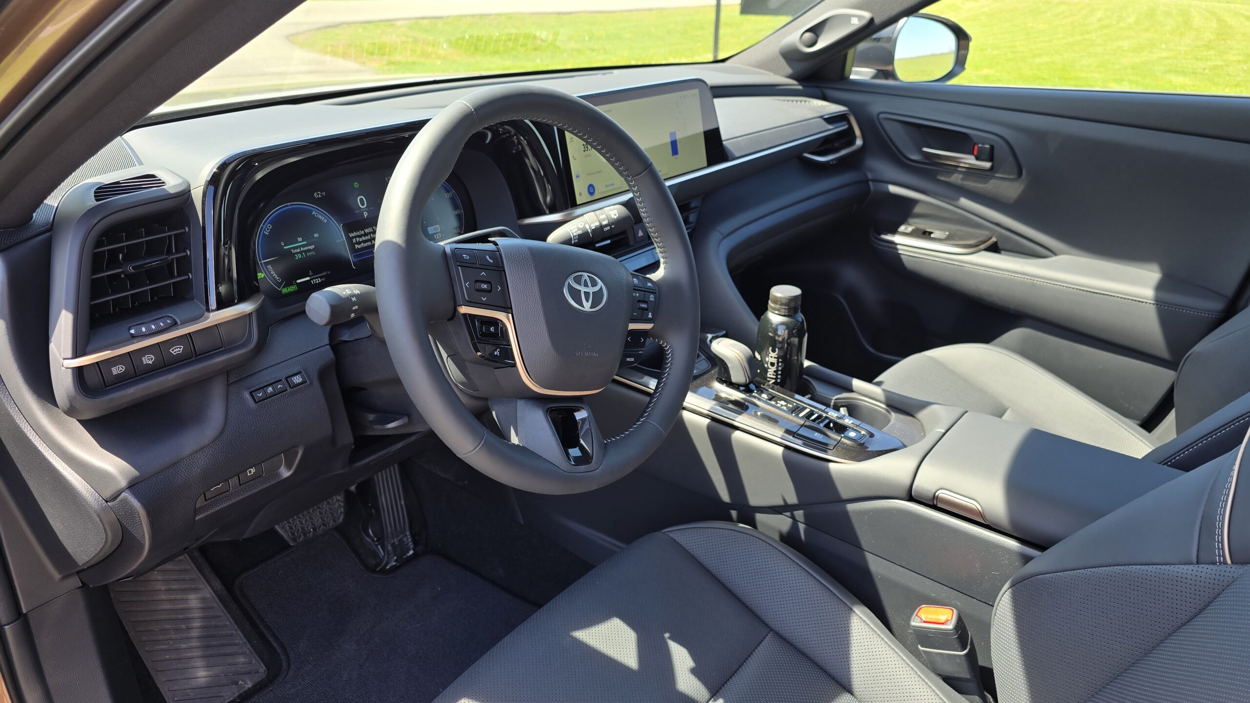 Interior view of the Toyota Crown Signia front cabin highlighting the leather-wrapped steering wheel, digital dashboard, and center console