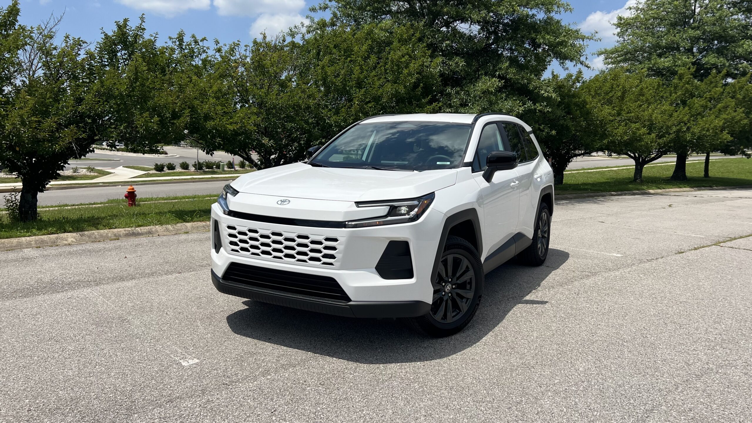 Front three-quarter view of a white 2026 Toyota RAV4 XLE Premium, showcasing its gray 18-inch alloy wheels and body color grille.