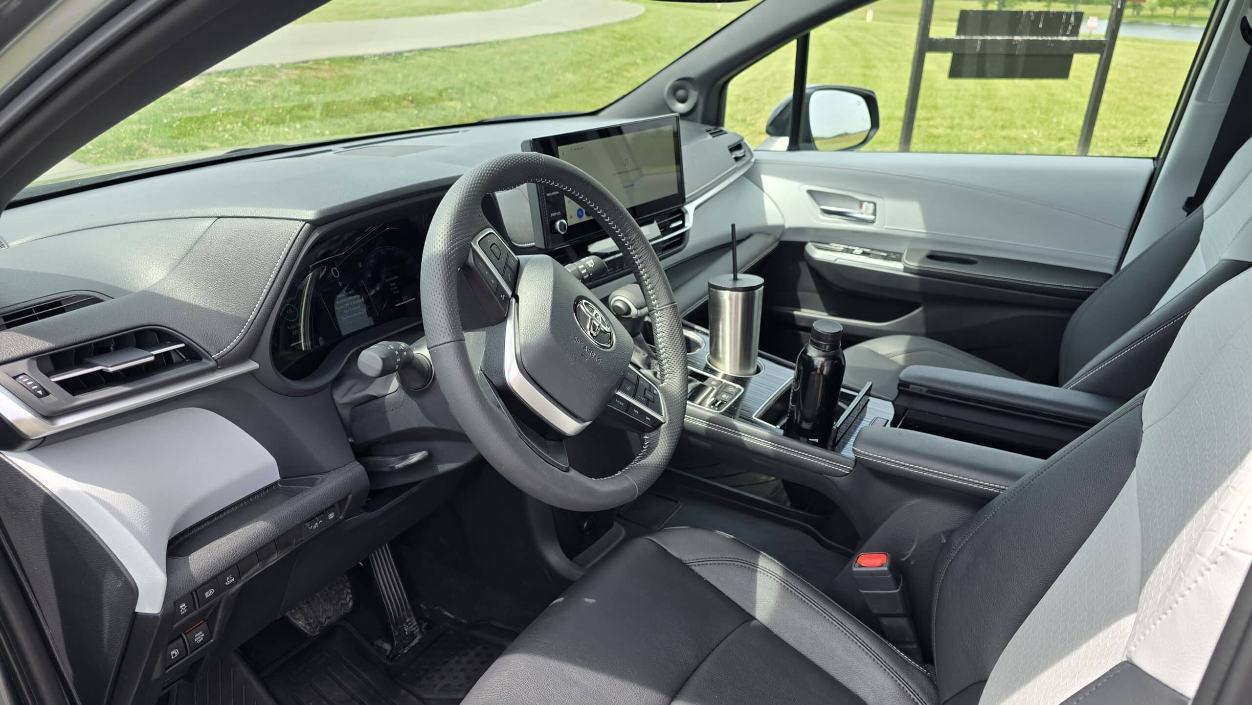 Driver's seat perspective of a Toyota interior, featuring the steering wheel, digital instrument cluster, and center infotainment screen