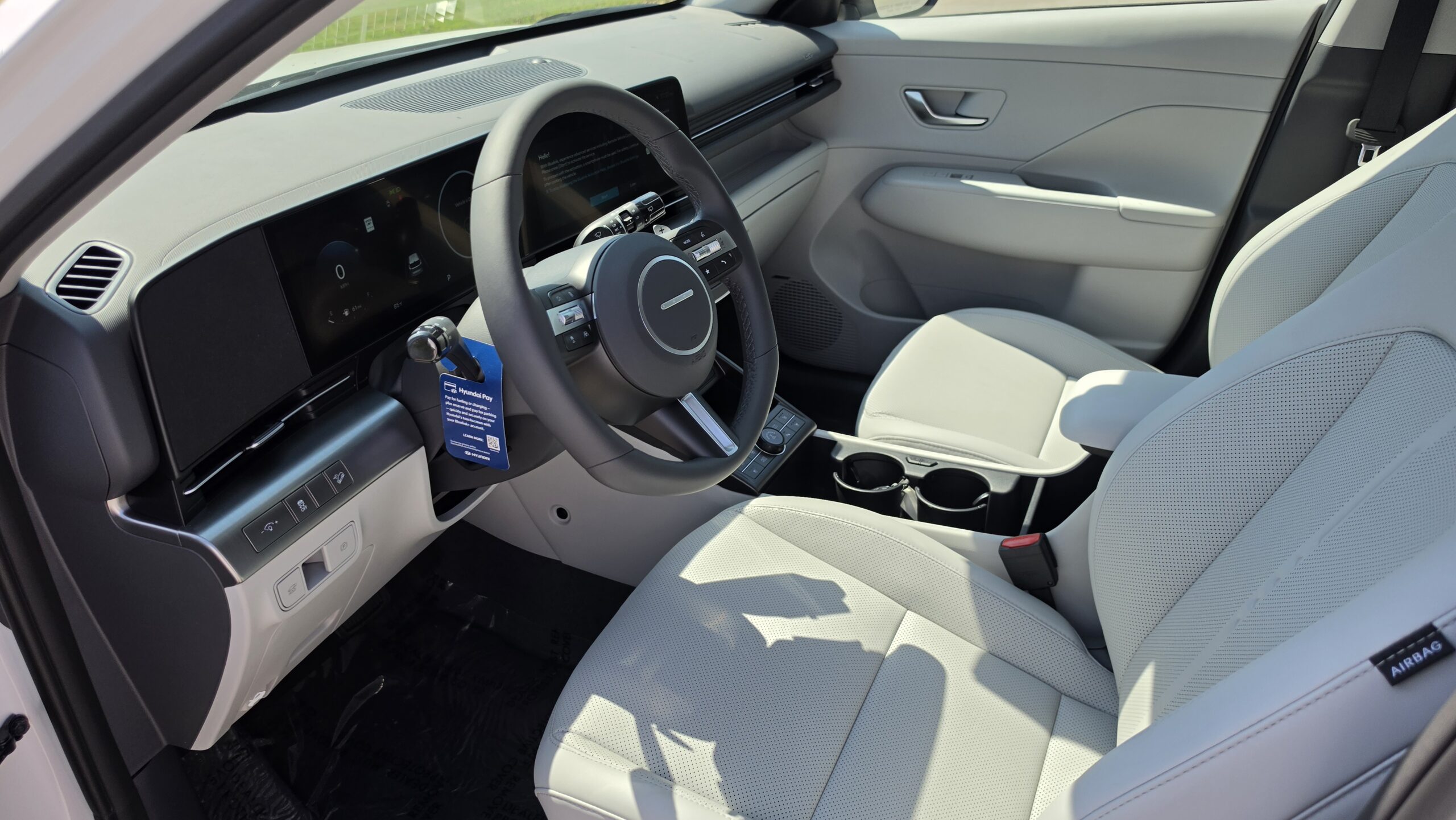Interior cabin view of the 2027 Hyundai Kona featuring the driver's steering wheel, digital dashboard, and infotainment screens.
