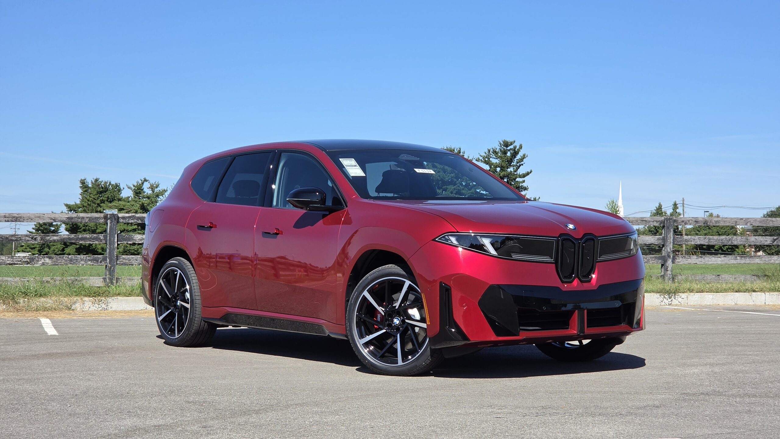 2027 BMW iX3 front three-quarter view showing the red exterior paint, modern closed kidney grille, and sleek LED headlights.