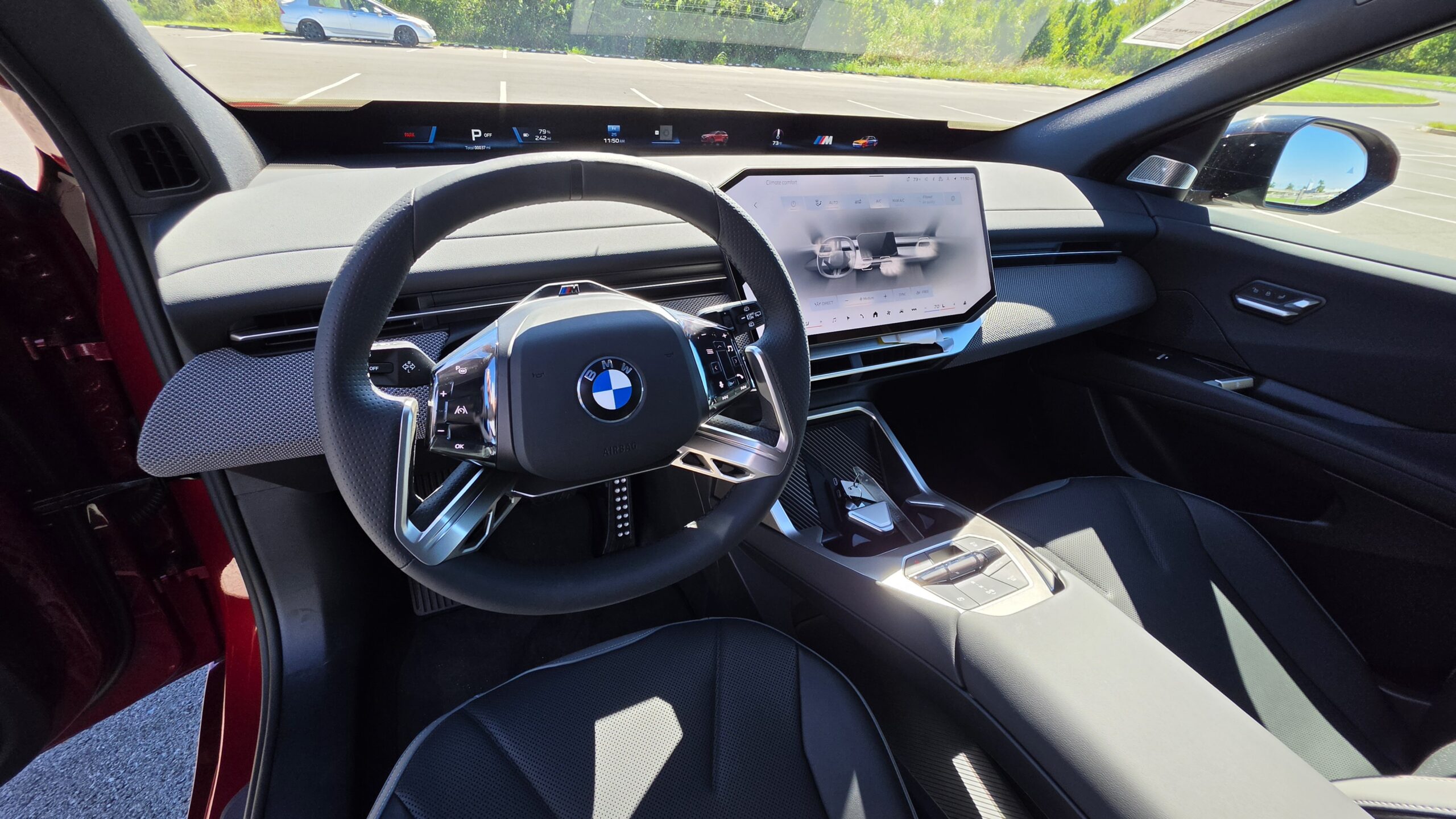 2027 BMW iX3 interior cabin view focused on the leather steering wheel, modern curved digital gauge cluster, and central infotainment display.